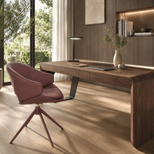 Load image into Gallery viewer, A modern home office scene featuring a dark wood writing desk with a sculptural black metal leg, a matching swivel chair in dusty rose, and a minimalist lamp on a light wood floor.