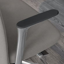 Load image into Gallery viewer, Close-up of an Alto office chair armrest with a dark gray padded top and a polished silver metal frame, set against a grey textured fabric seat and a grey wood-look floor.
