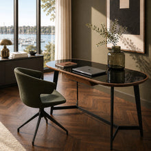 Load image into Gallery viewer, A modern oval desk with a glossy black top and dark metal legs, styled in a sunlit home office with a green velvet swivel chair, a laptop, and a glass vase on top. The room features a herringbone wood floor, a large window overlooking a marina, and warm neutral walls.
