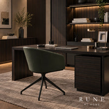 Load image into Gallery viewer, A modern home office setup featuring a dark wood writing desk with a matching pedestal drawer, a dark green Rune swivel office chair, and a textured beige rug, set against a background of dark wood shelving with warm lighting.
